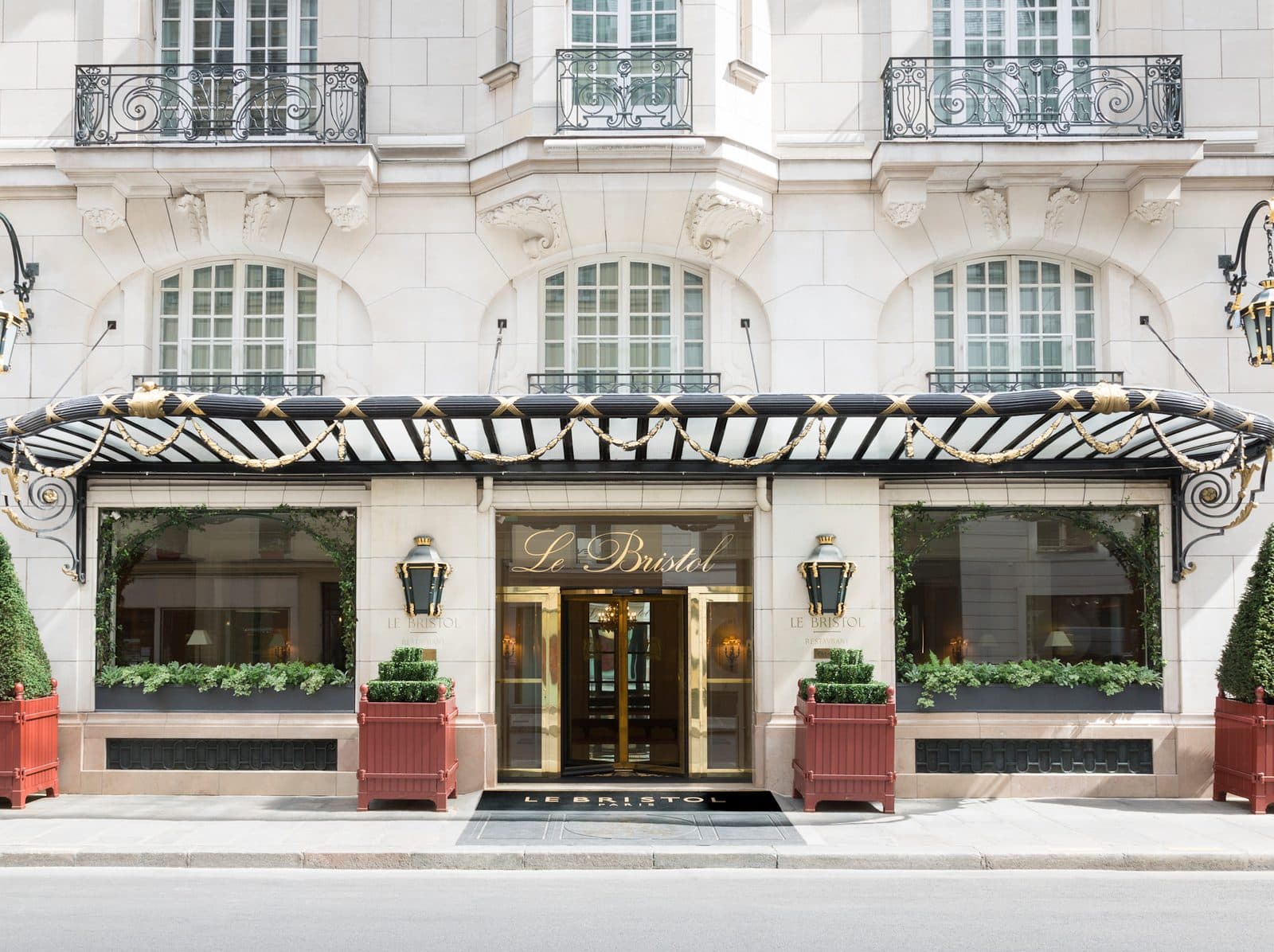 The entrance to Le Bristol Paris beneath a wrought-iron canopy on a pale façade with balconies
