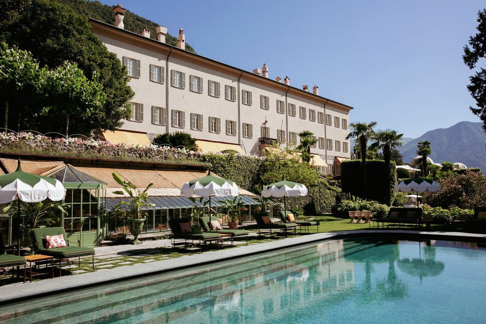 The main Passalacqua villa above the outdoor pool, with white umbrellas and green garden terraces