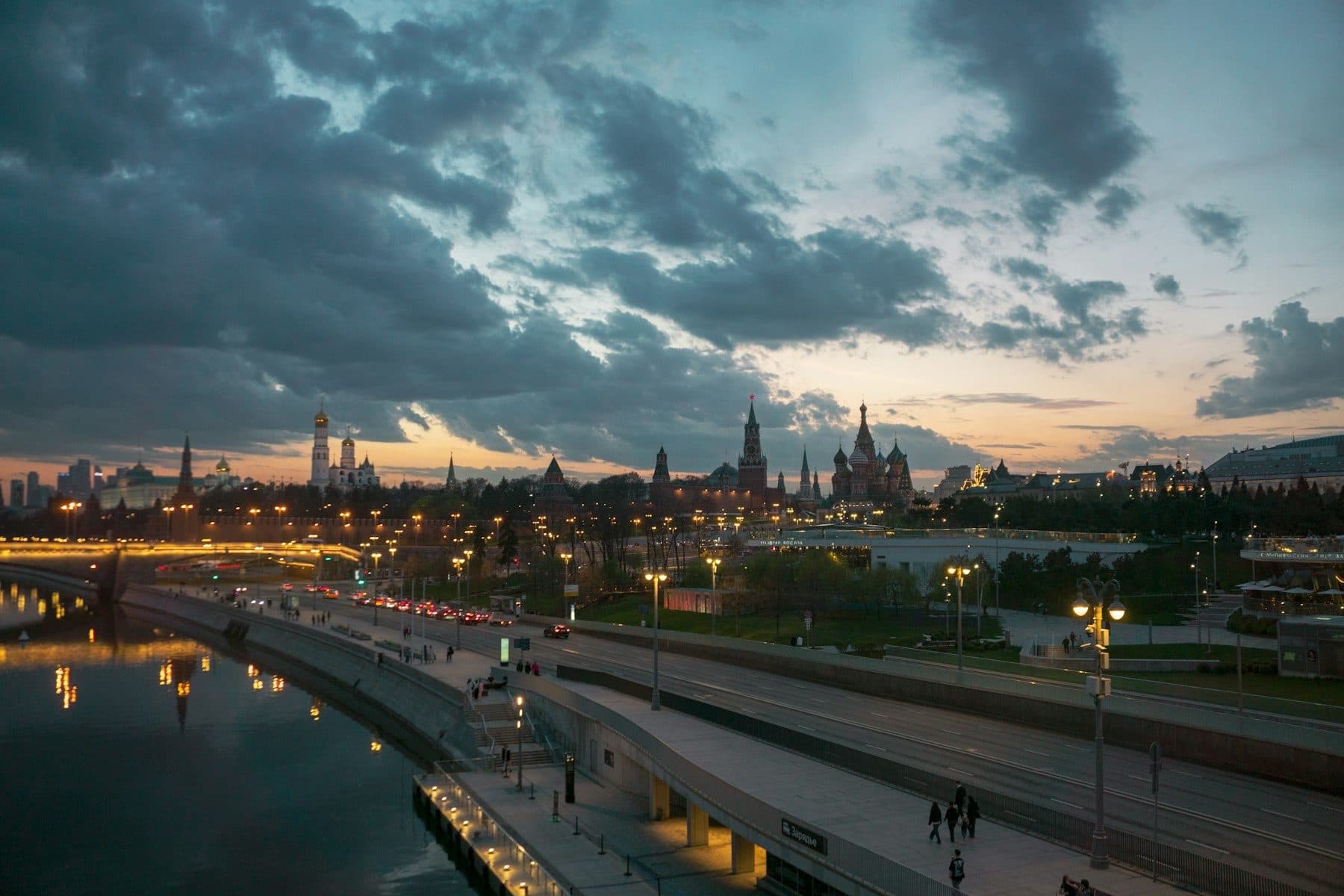 Moscow in the evening from the bridge in Zaryadye: cars on Moskvoretskaya Embankment, the Kremlin and St Basil's Cathedral under a cloudy sky.