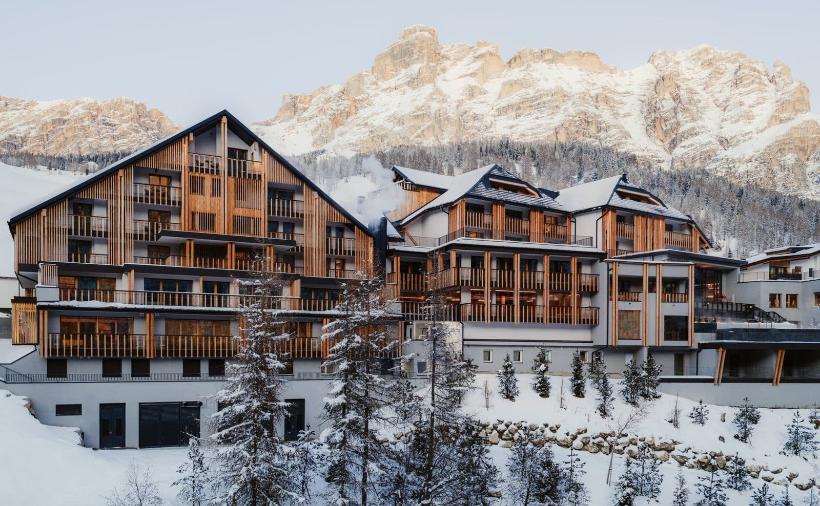 Wooden Aman Rosa Alpina buildings in snow against rocky peaks