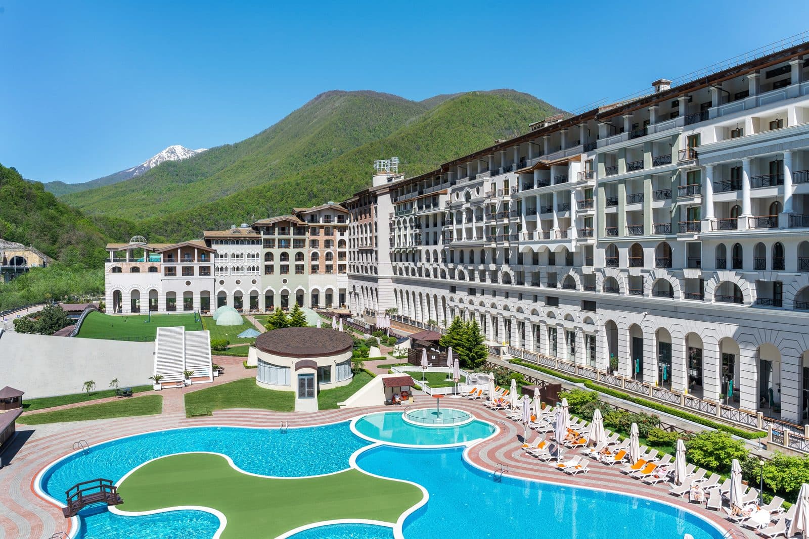 Marriott buildings and pools with rounded islands against green mountains