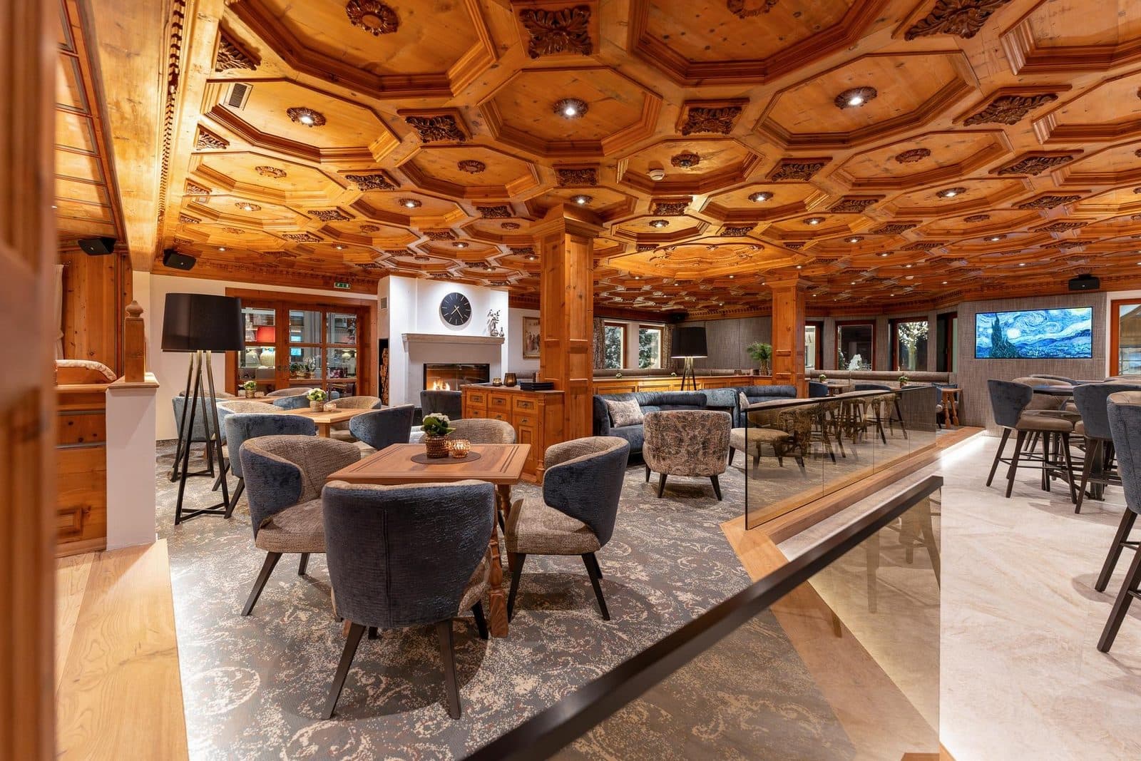 A lounge with a carved wooden ceiling, bar counter and armchairs at tables