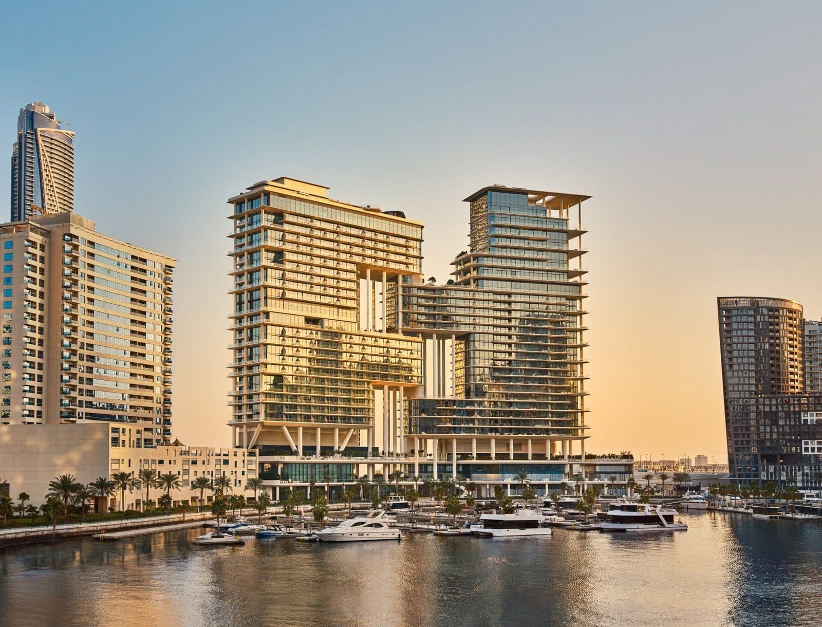 The Lana at sunset: two buildings with offset floors above Marasi Marina, with yachts at the jetty