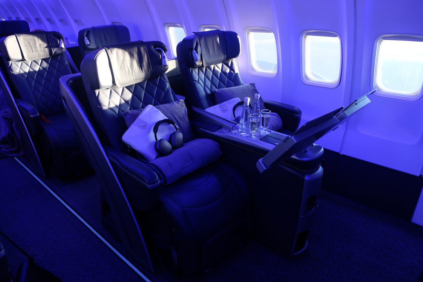 Lujo BlackJet cabin: paired business-class seats, individual screens and blue lighting.